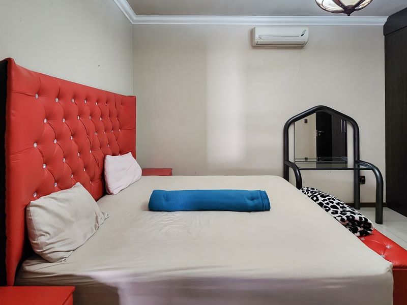 A bedroom featuring tiled flooring, crown molding, a built-in wardrobe, and a wall-mounted split-system air conditioner.