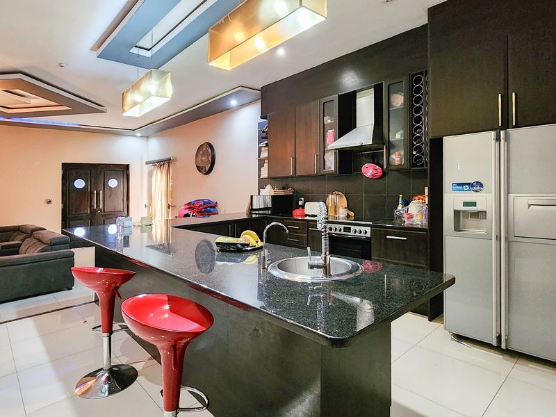 Spacious open-plan kitchen and living area featuring dark cabinetry, a large granite island with integrated sink, and modern recessed ceiling lighting.