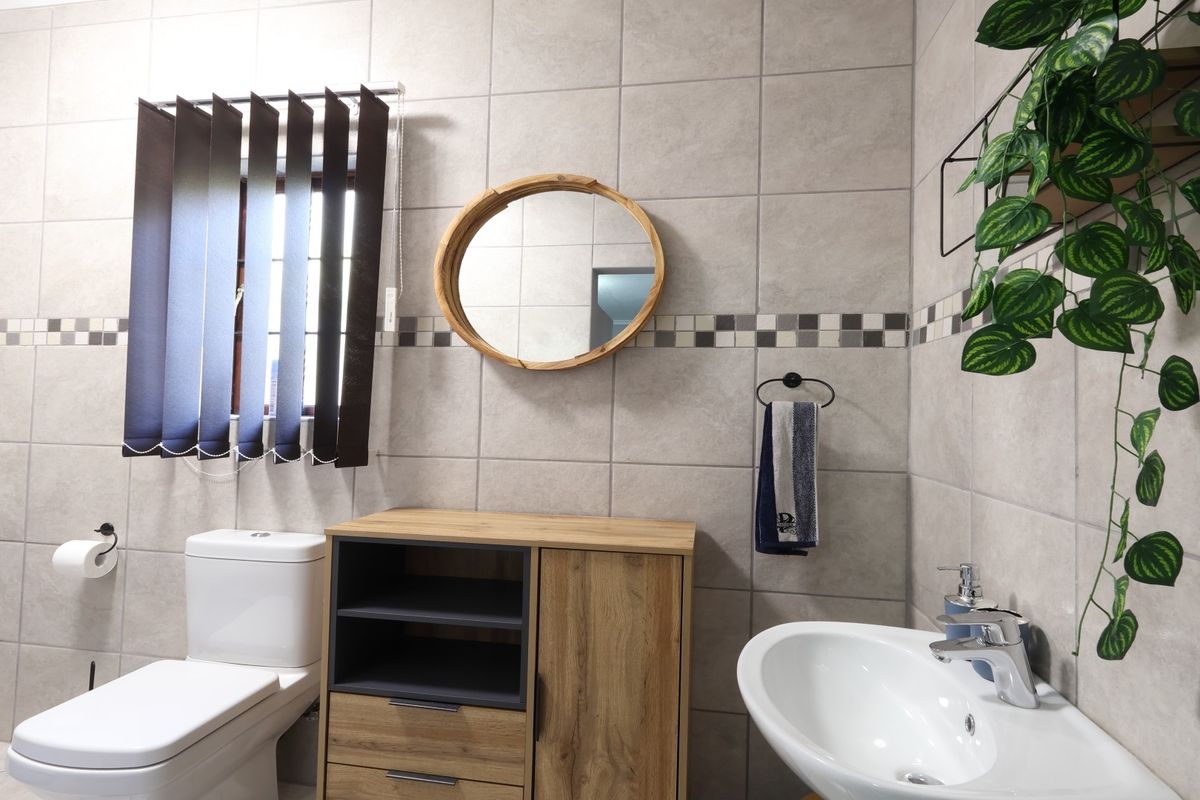 A well-maintained bathroom featuring neutral ceramic wall and floor tiles, a modern washbasin with mixer tap, and a standard toilet.
