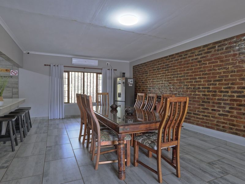 Dining room featuring an exposed brick feature wall, tiled flooring, and a breakfast bar, providing a rustic yet functional space for meals.