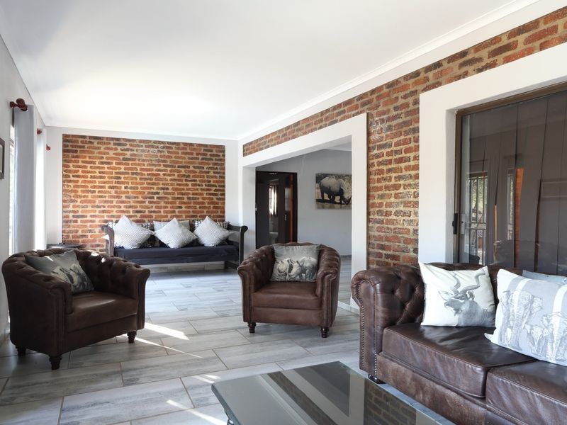 Spacious living area featuring exposed brick walls, neutral tiled flooring, and large sliding glass doors providing natural light and access to the exterior.