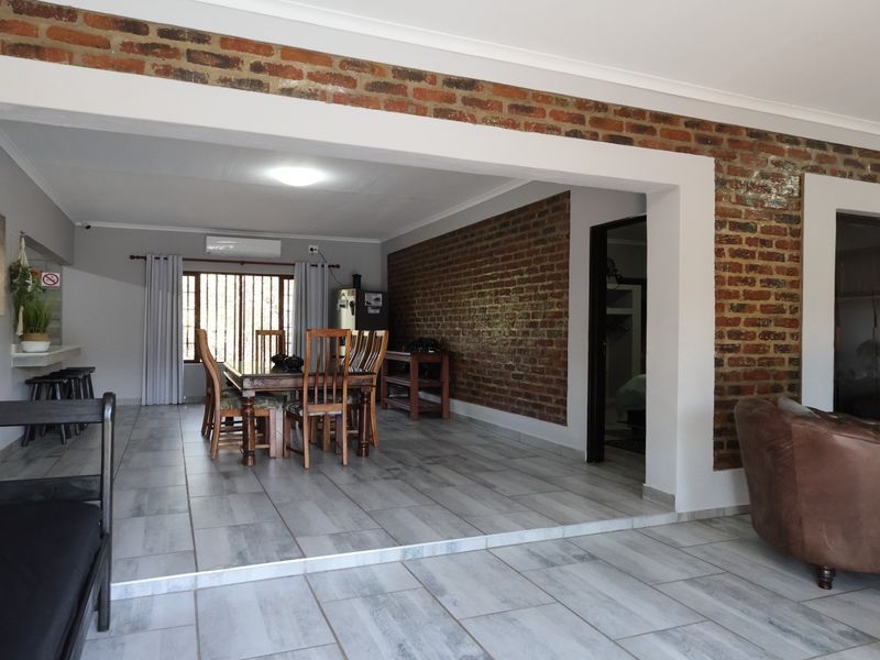 Spacious open-plan living and dining area featuring exposed brick walls, modern tiled flooring, and an integrated breakfast bar.