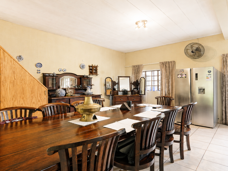 A spacious dining room featuring tiled flooring, built-in wooden cabinetry, and a ceiling fan, providing a functional area for family meals and gatherings.