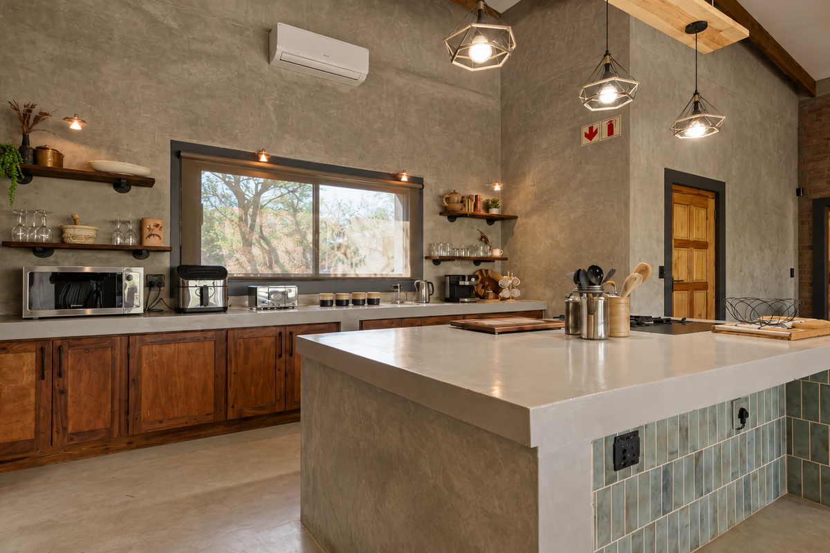 Modern industrial-style kitchen featuring a large concrete island, custom wooden cabinetry, exposed brick accents, and high-quality pendant lighting.