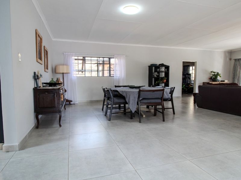 Spacious open-plan living and dining area featuring neutral tiled flooring, large steel-framed windows, and clean, well-maintained wall finishes.
