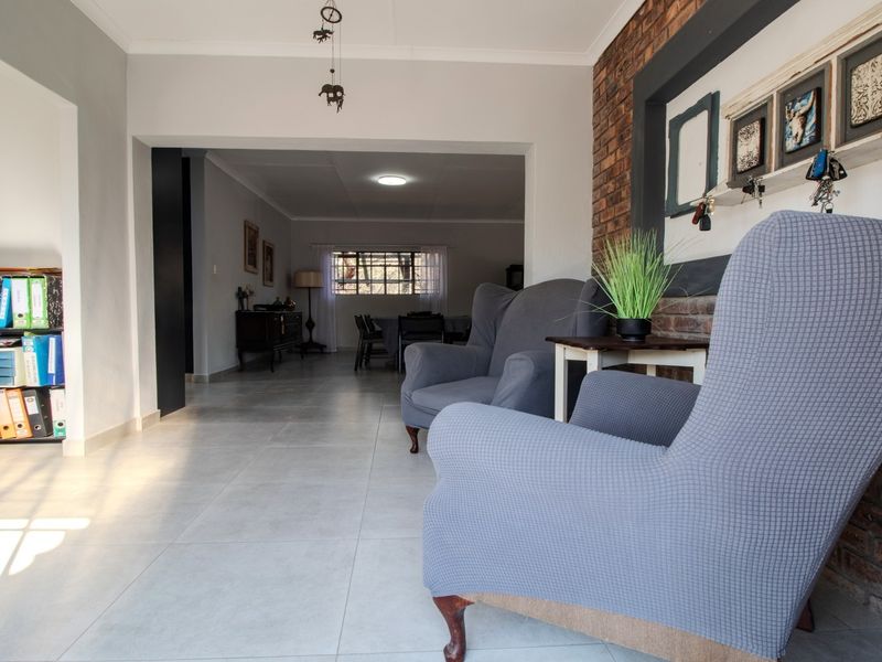 Spacious open-plan living area featuring tiled flooring and an exposed brick feature wall, creating a warm and inviting atmosphere.