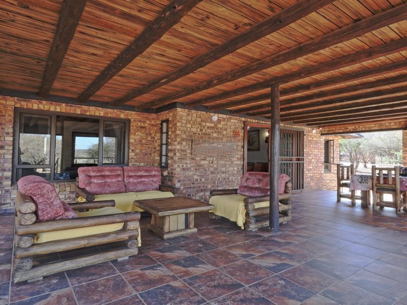 A spacious covered patio featuring rustic facebrick walls, exposed timber beam ceilings, and durable tiled flooring, ideal for outdoor relaxation and entertaining.