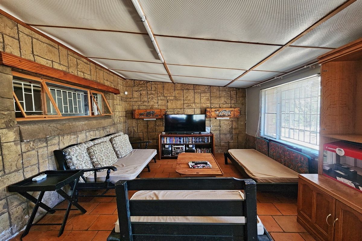 A living room featuring stone-clad walls, terracotta floor tiles, and a suspended ceiling, offering a dated aesthetic with potential for modernization.