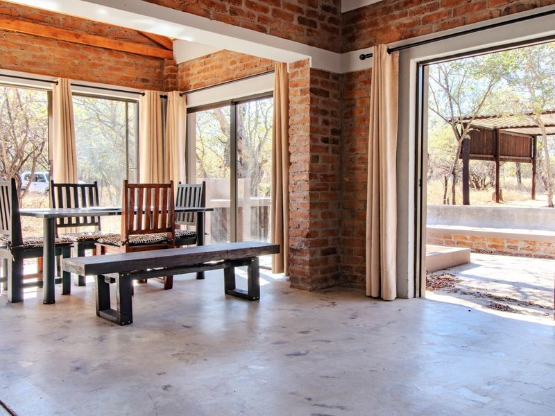 Open-plan living area featuring exposed brick walls, polished concrete floors, and large sliding glass doors providing seamless access to the outdoor patio.