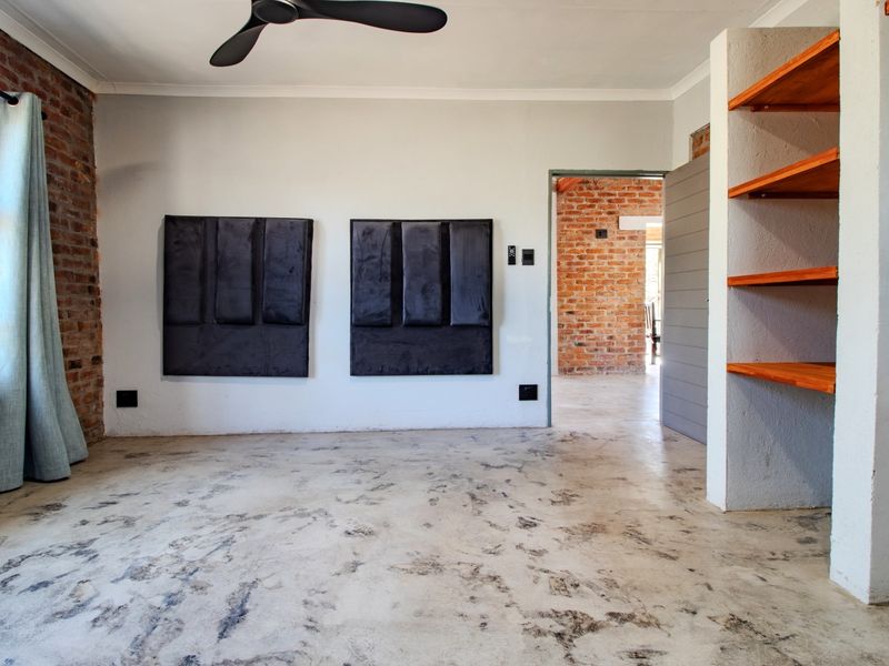 Spacious bedroom featuring industrial-style exposed brick walls, polished concrete floors, and built-in shelving, offering a modern and minimalist aesthetic.