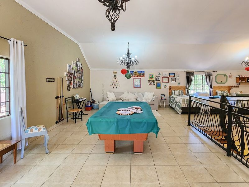 Spacious open-plan bedroom area featuring vaulted ceilings, tiled flooring, and a wrought iron balustrade overlooking the lower level.