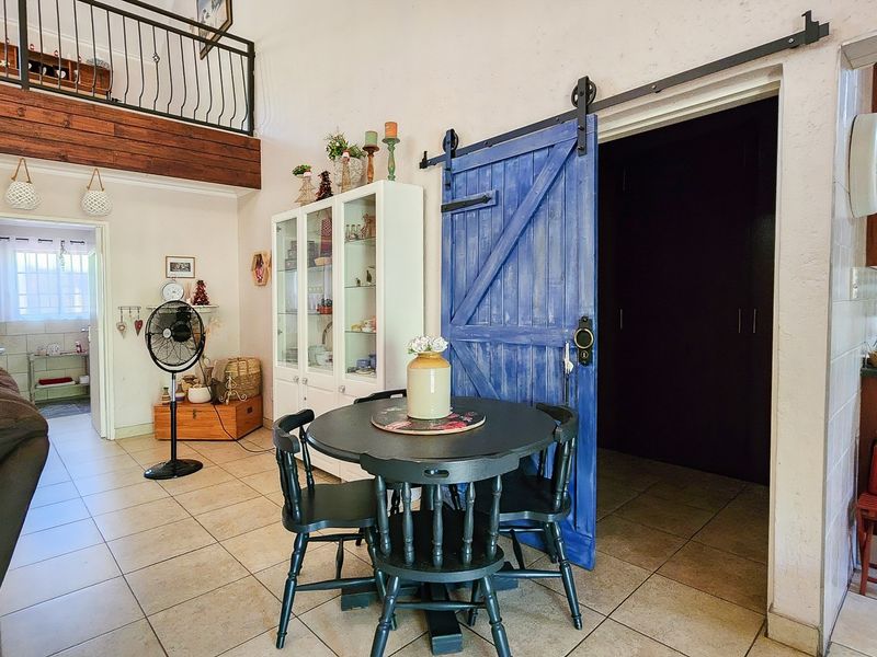 Open plan living area featuring tiled floors, a mezzanine level with wrought iron railing, and a distinctive blue sliding barn door.