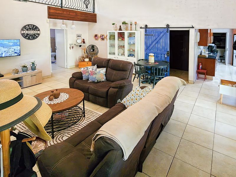 Open-plan living area featuring tiled floors, a mezzanine level with wrought iron railing, and a distinctive blue sliding barn door leading to adjacent spaces.