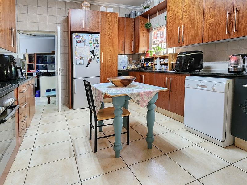 A functional kitchen featuring warm-toned wooden cabinetry, granite countertops, tiled flooring, and a built-in oven with a gas hob.