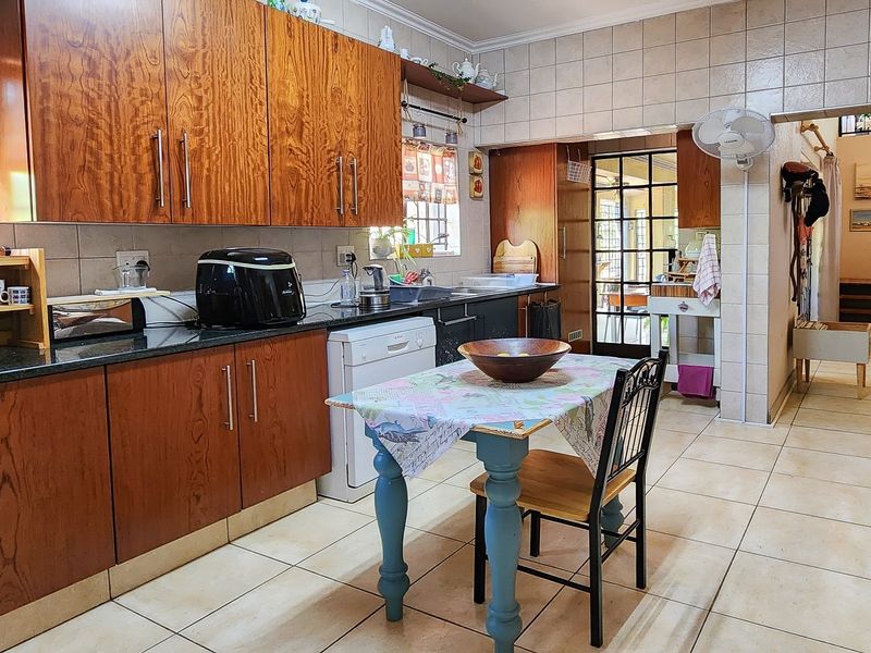 A functional kitchen featuring wooden cabinetry, granite countertops, tiled backsplash, and tiled flooring, with a direct view into the adjacent living area.