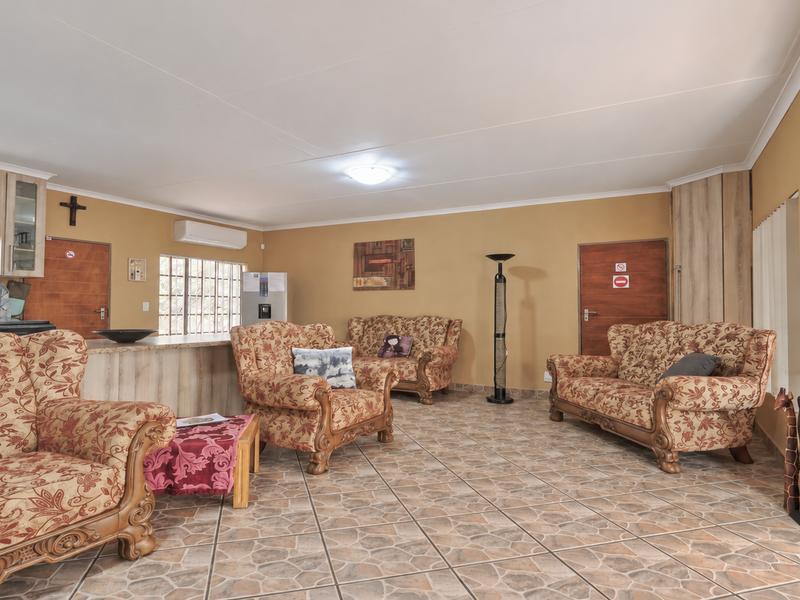 Spacious open-plan living area featuring tiled flooring, a breakfast bar, and integrated kitchen cabinetry, with direct access to the exterior.