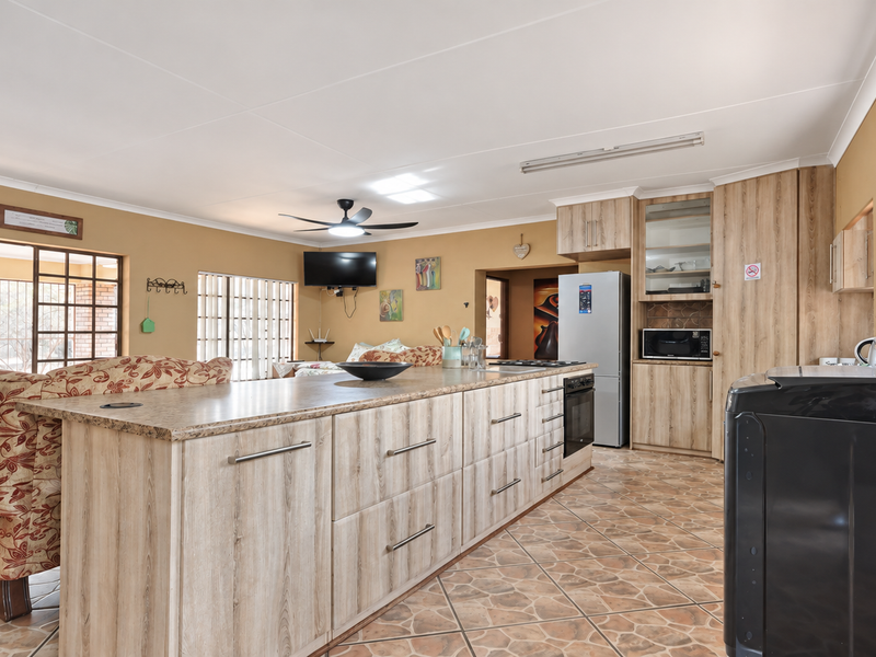 Spacious open-plan kitchen and living area featuring a large central island, laminate cabinetry, and tiled flooring throughout.