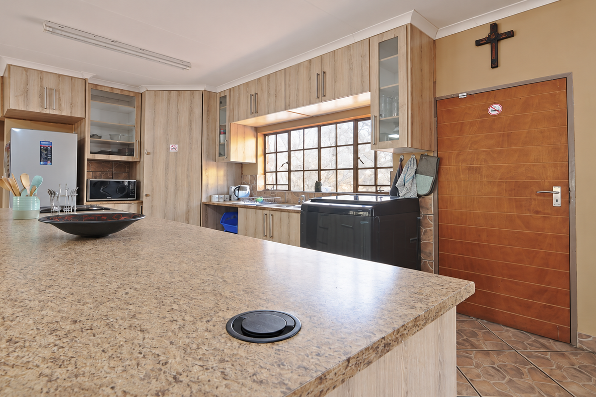 A functional kitchen featuring laminate cabinetry, a large island with a granite-look countertop, and tiled flooring, offering ample workspace and storage.