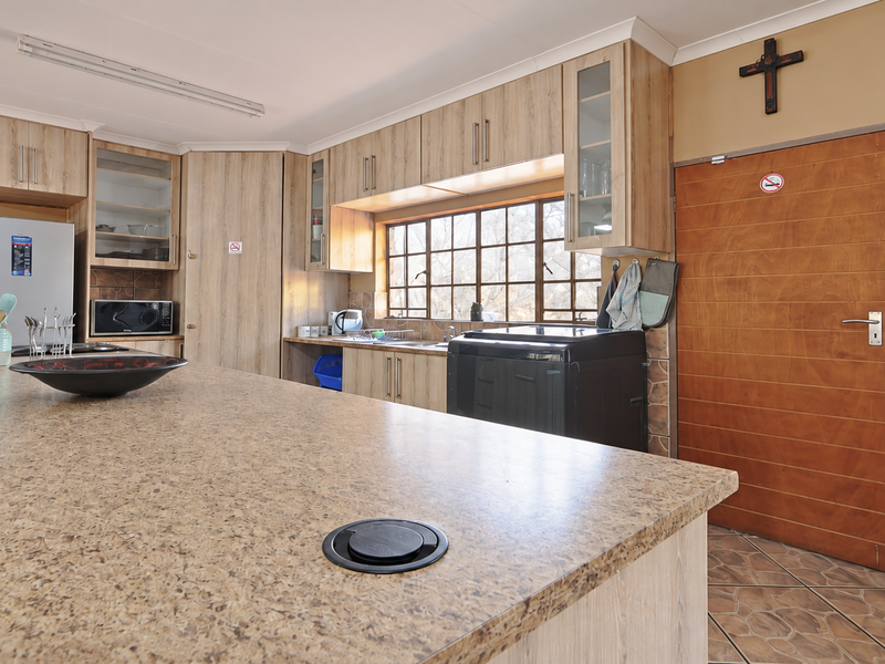 A functional kitchen featuring laminate cabinetry, a large island with a granite-look countertop, and tiled flooring, offering ample workspace and storage.