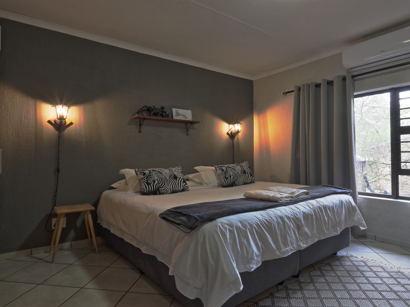 A well-maintained bedroom featuring tiled flooring, a built-in wardrobe, and a wall-mounted air conditioning unit.