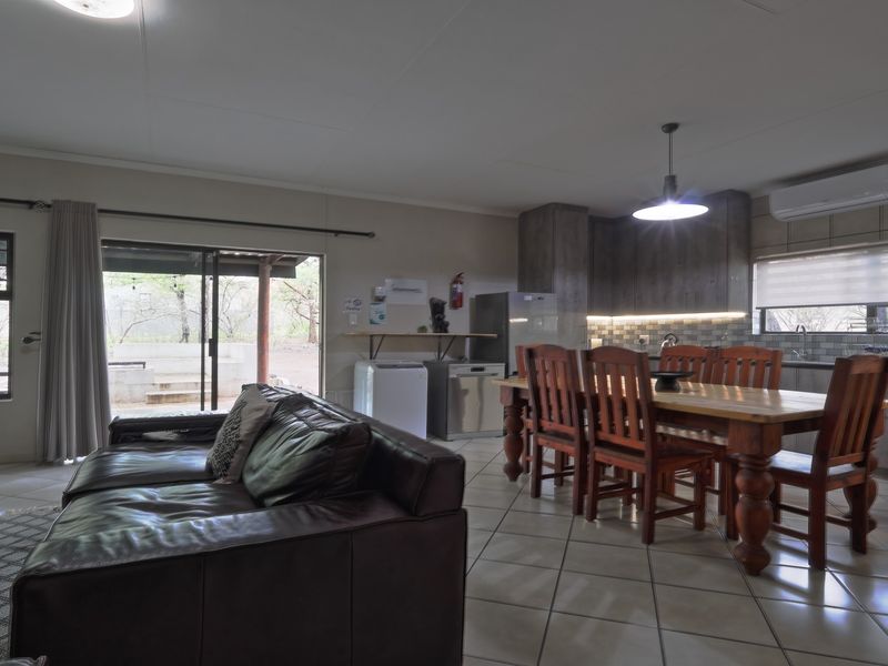 Spacious open-plan living and dining area featuring tiled floors, modern cabinetry, and direct access to an outdoor patio through sliding glass doors.
