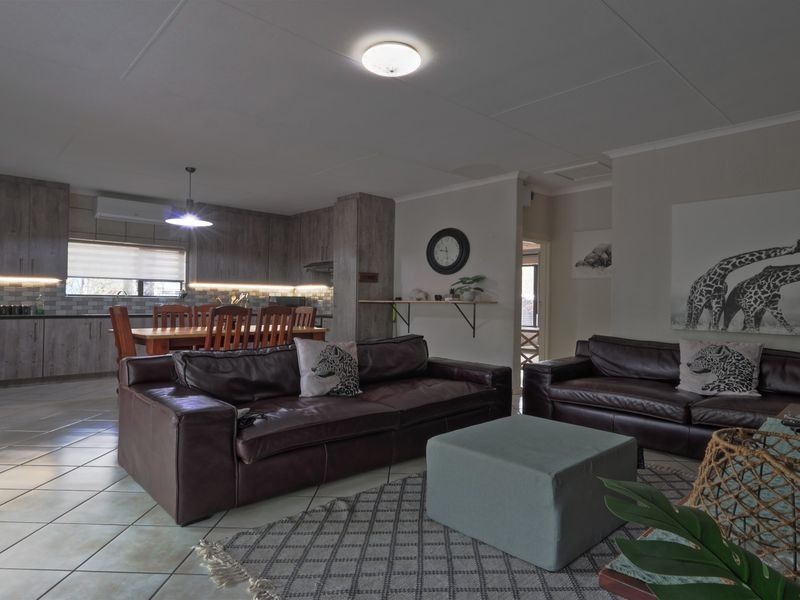 Spacious open-plan living and kitchen area featuring modern cabinetry, tiled flooring, and integrated lighting, creating a functional and cohesive family living space.