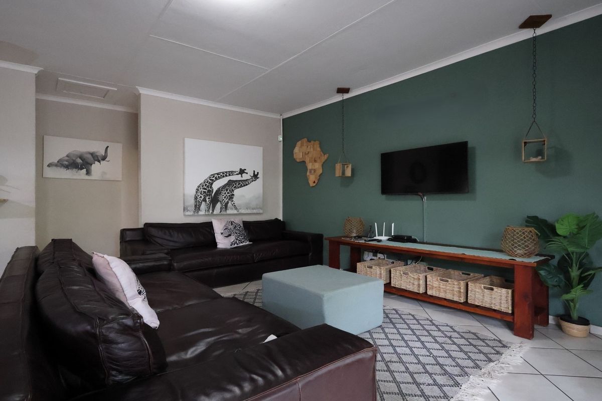 A comfortable living room featuring tiled flooring, a coved ceiling, and a prominent green accent wall.