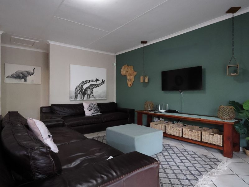 A comfortable living room featuring tiled flooring, a coved ceiling, and a prominent green accent wall.