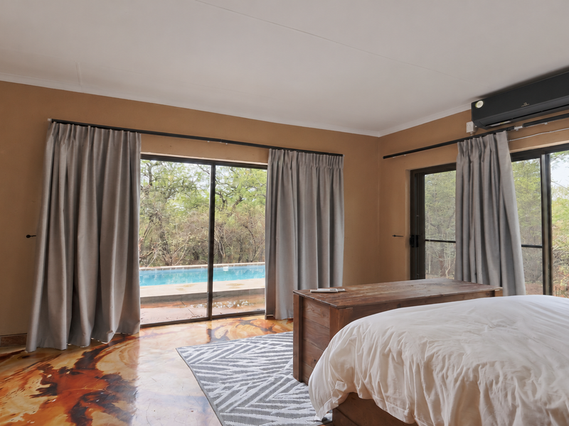 Spacious bedroom featuring unique epoxy resin flooring, split-system air conditioning, and large sliding glass doors providing direct access to the outdoor pool area.