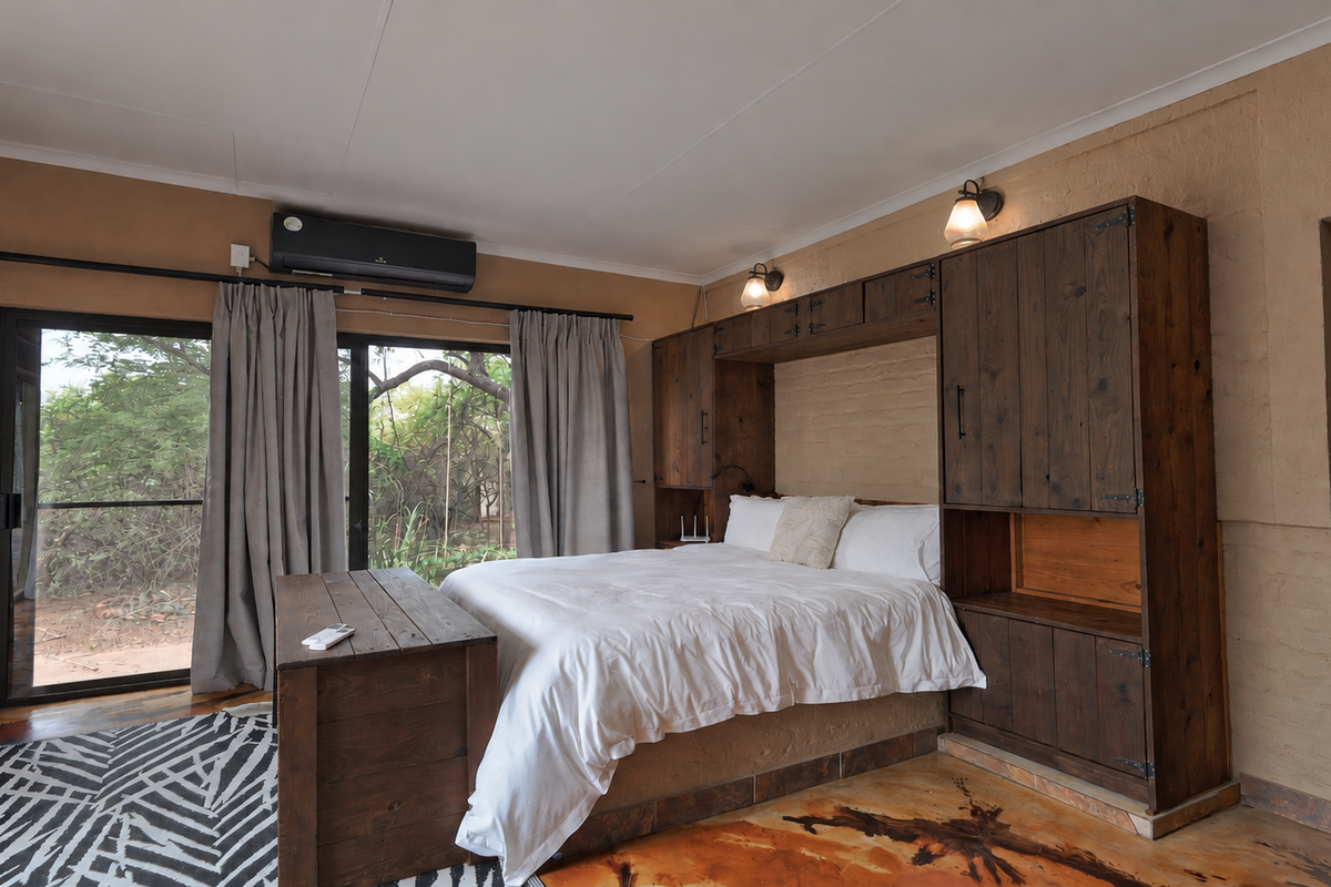 A rustic-style bedroom featuring built-in wooden cabinetry surrounding the bed, polished concrete floors, and a sliding glass door providing access to the outdoors.