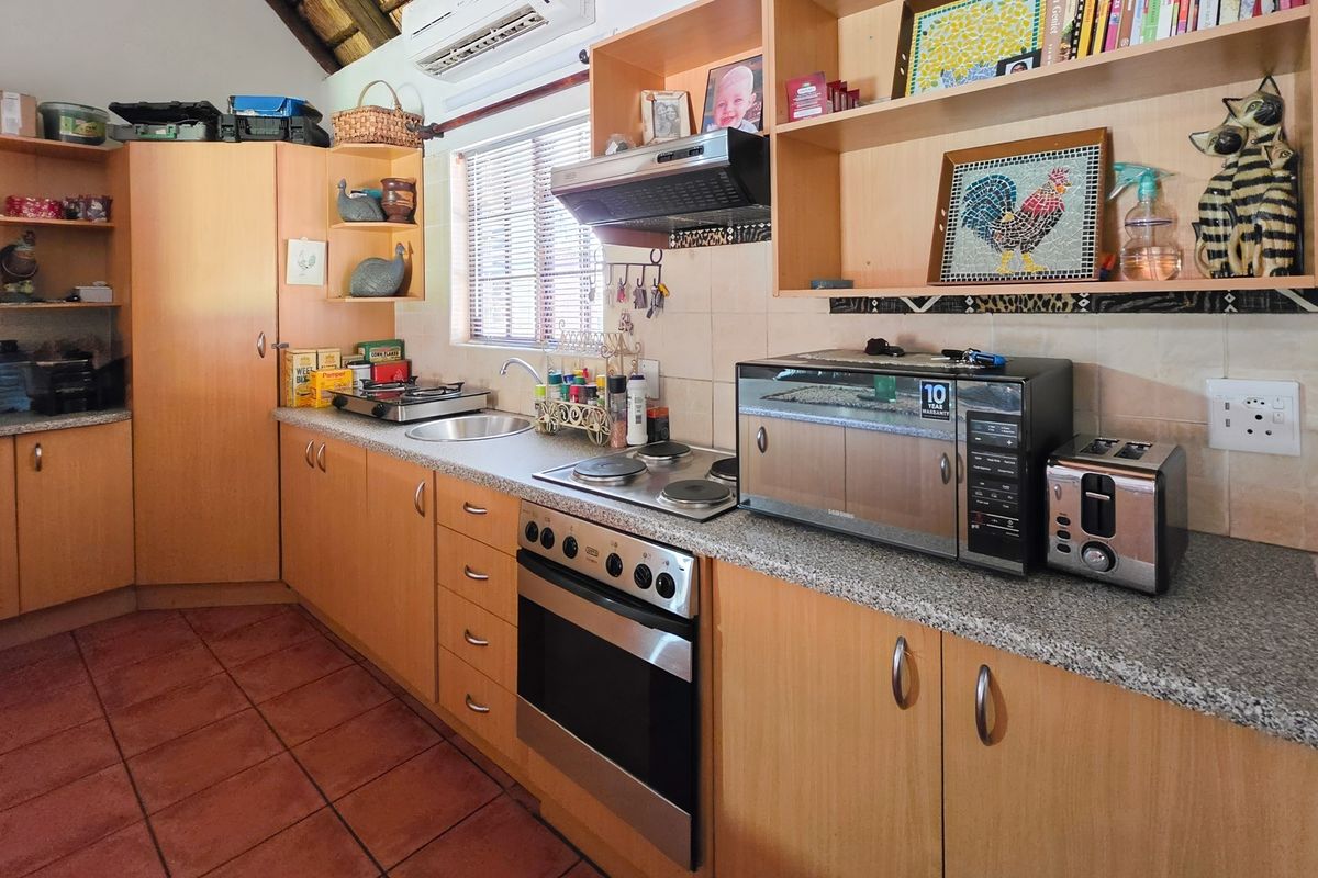 A functional kitchen featuring light wood cabinetry, granite countertops, a built-in oven with electric hob, and tiled flooring.