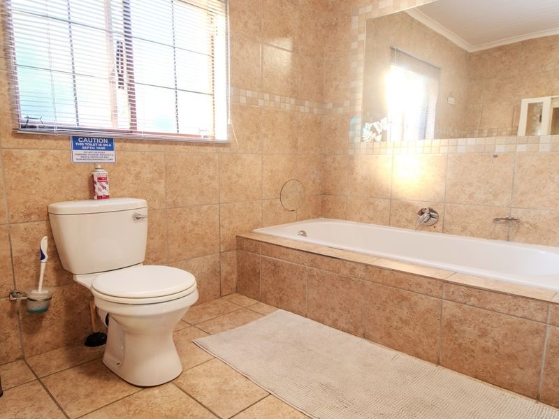 A functional bathroom featuring tiled walls and flooring, a built-in bathtub, and a standard toilet, offering a neutral and practical layout.