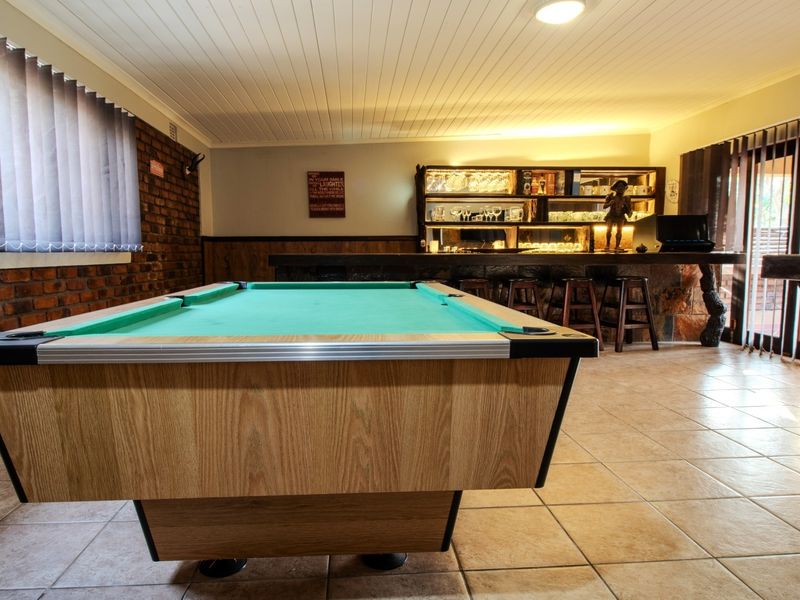 A dedicated entertainment bar area featuring a built-in bar counter, shelving, exposed brick accents, and tiled flooring, ideal for hosting and social gatherings.