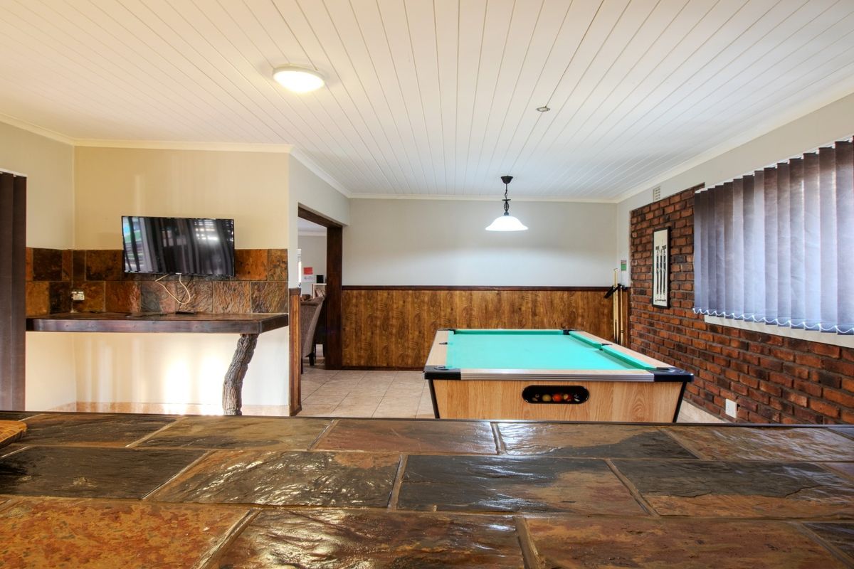 Spacious living area featuring exposed brickwork, slate tile accents, timber wall paneling, and a tongue and groove ceiling with tiled flooring throughout.