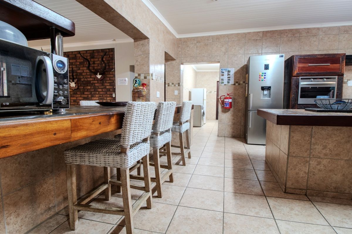 Spacious kitchen featuring tiled finishes, a built-in oven and hob, breakfast counter, and direct access to a secondary utility or scullery area.