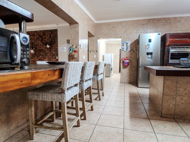 Spacious kitchen featuring tiled finishes, a built-in oven and hob, breakfast counter, and direct access to a secondary utility or scullery area.