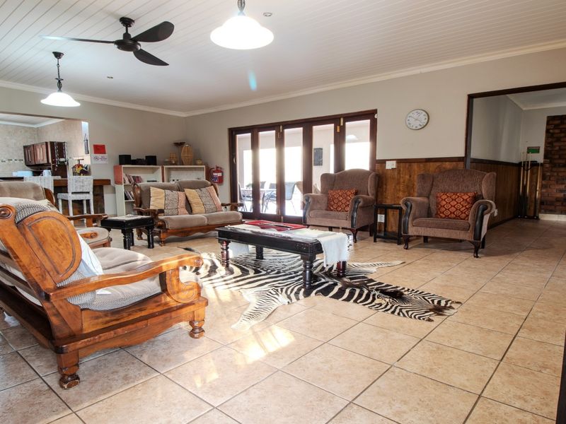Spacious open-plan living area featuring tiled floors, exposed brick accents, wood paneling, and bi-fold doors leading to the outdoor space.
