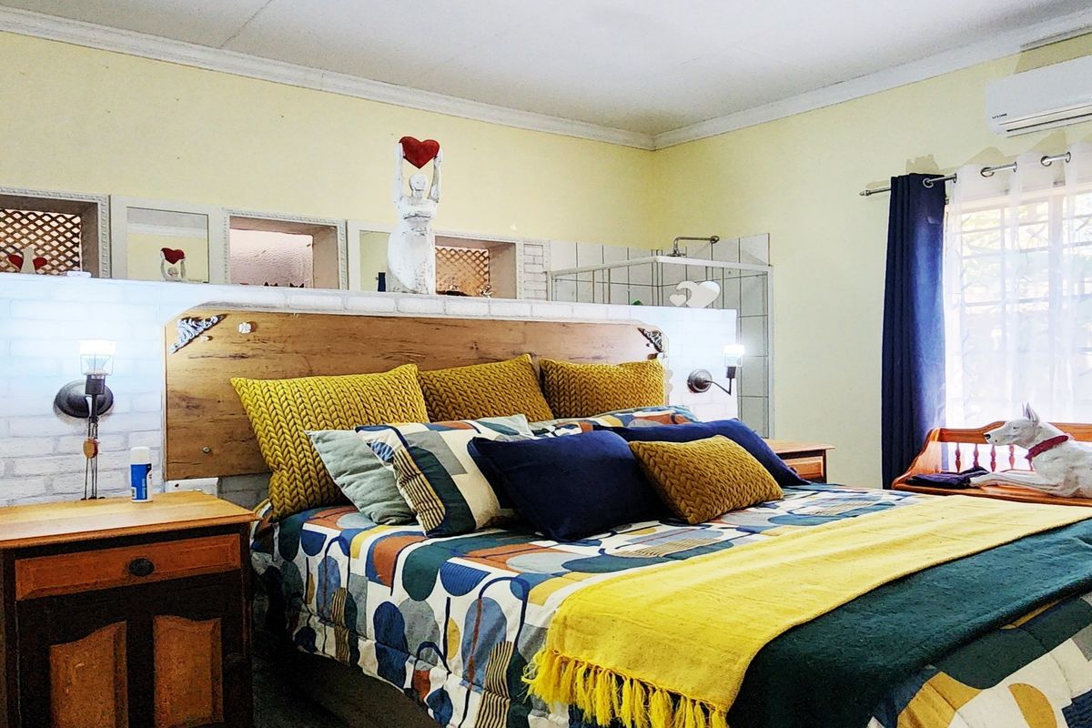 A bedroom featuring a unique open-plan layout with a central brick-style partition wall, integrated headboard, and an en-suite shower area.