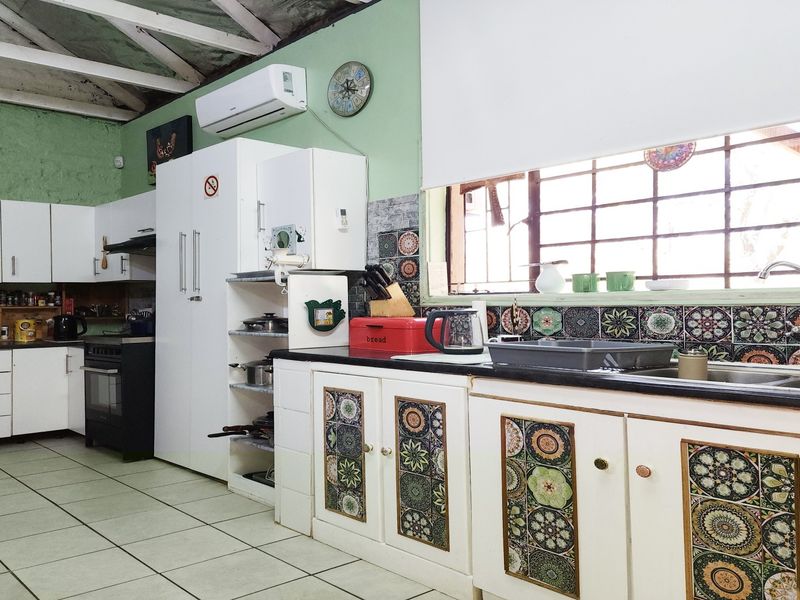 A functional kitchen featuring tiled flooring, built-in cabinetry with decorative accents, a double sink, and an exposed beam ceiling with air conditioning.
