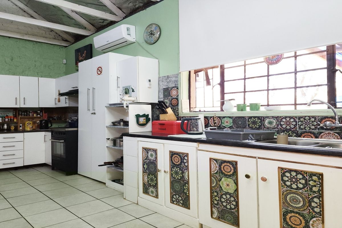 A functional kitchen featuring tiled flooring, built-in cabinetry with decorative accents, a double sink, and an exposed beam ceiling with air conditioning.