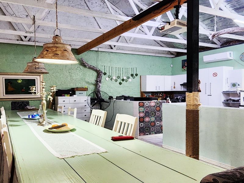 Open-plan living and dining area featuring exposed timber roof trusses, a tiled kitchen island, and split-system air conditioning.