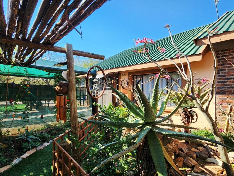 Rear exterior view of the property featuring a corrugated metal roof, exposed brick facade, and a timber pergola structure over a garden area.