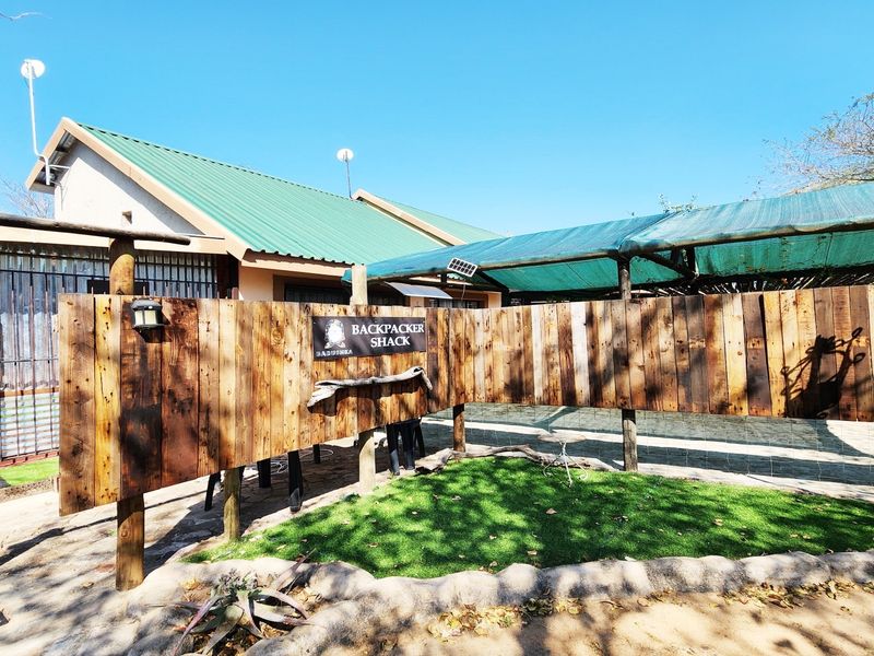 Rear exterior view featuring a paved patio area, artificial turf, timber privacy screen, and a shaded outdoor structure.