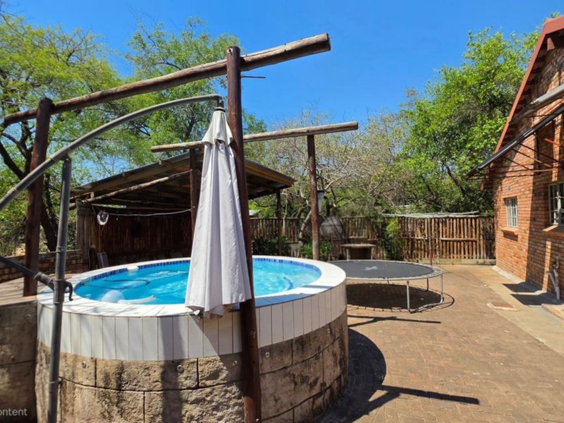 Outdoor pool area featuring a raised circular swimming pool with tiled coping, set within a brick-paved courtyard adjacent to the main house.