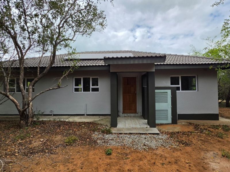 Front elevation of a single-story house featuring a tiled roof with solar panels, aluminium windows, and a covered entrance porch.