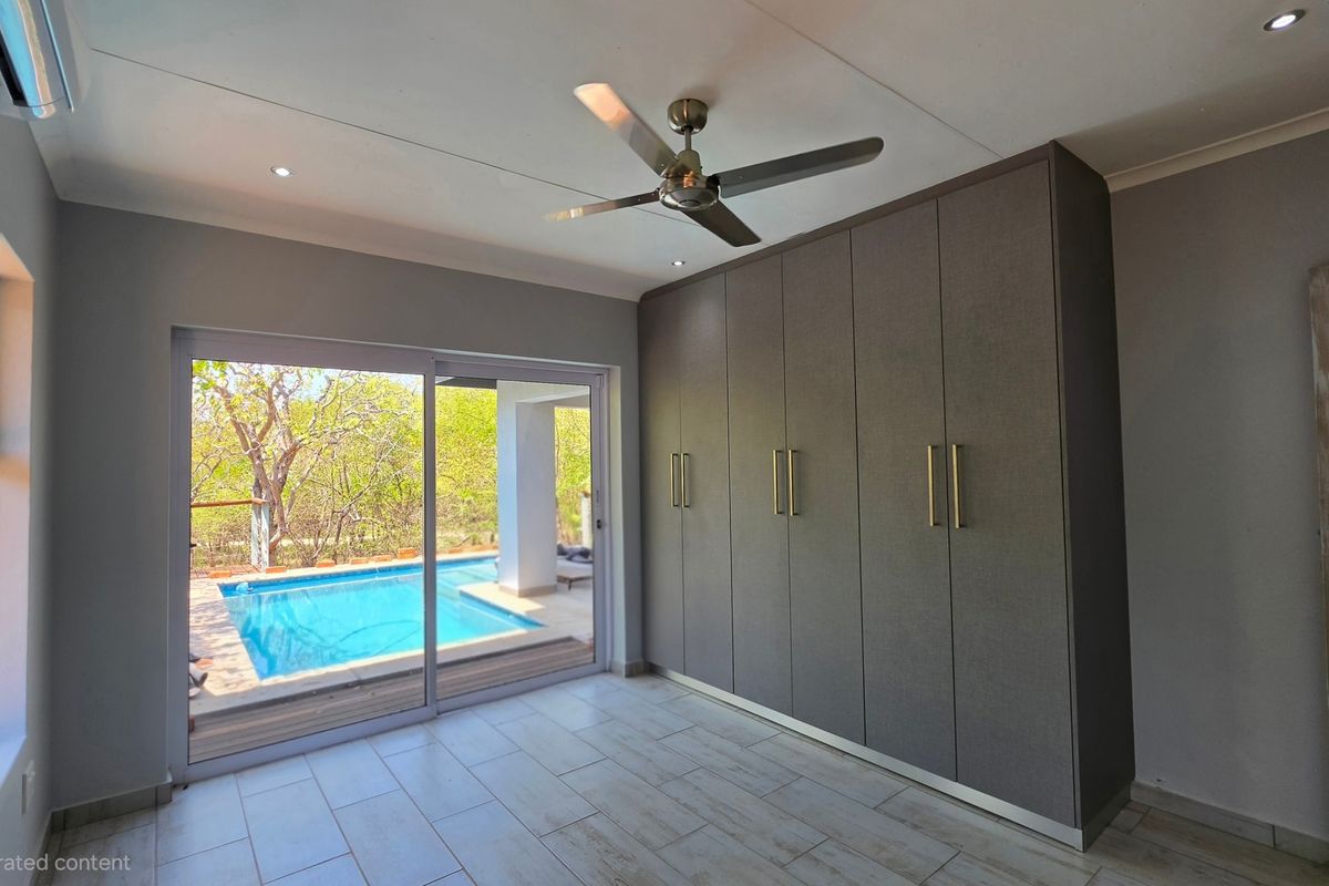 Modern bedroom featuring built-in cupboards, tiled flooring, and a sliding glass door providing direct access to the outdoor pool area.