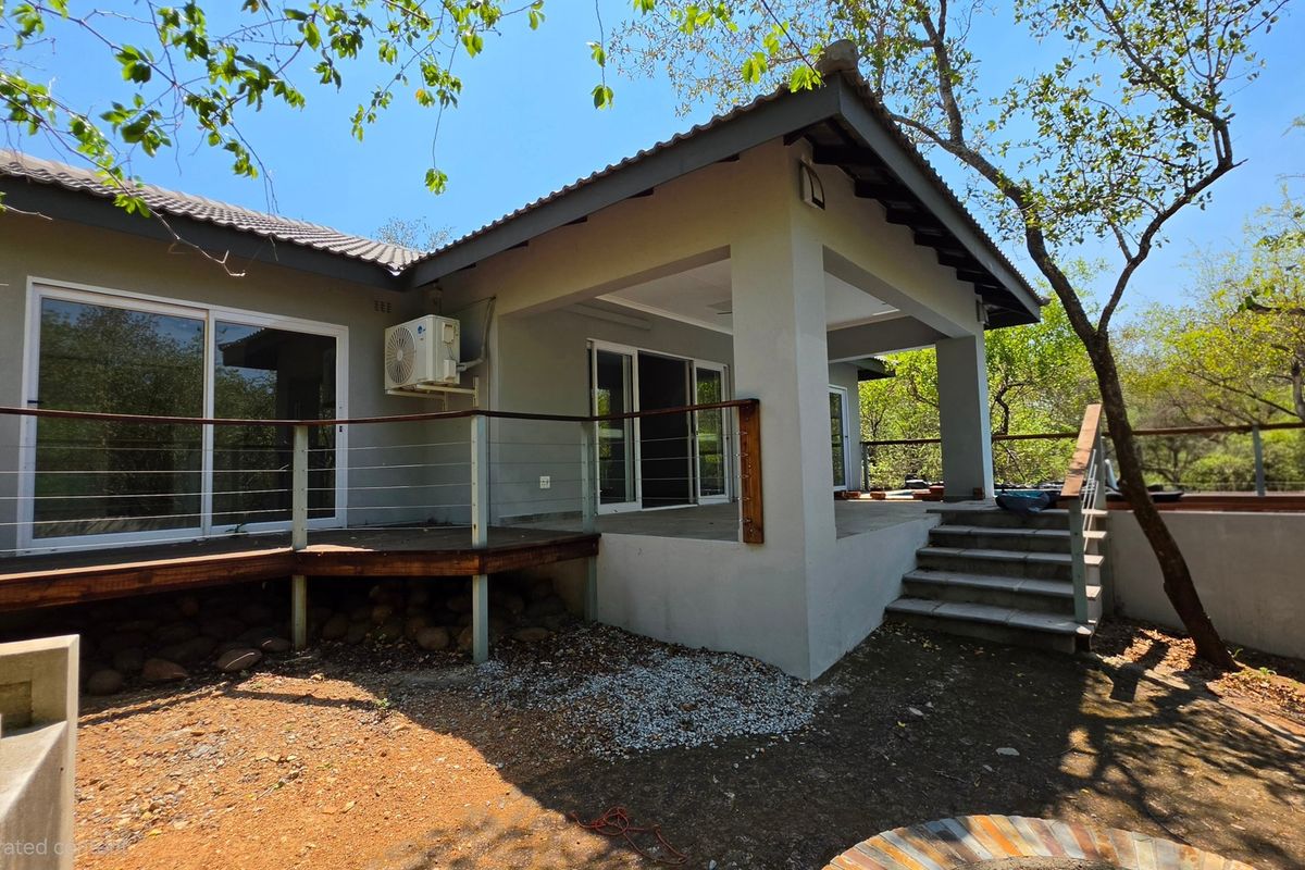 Rear view of the house featuring a covered patio, timber decking, and sliding glass doors leading into the living area.