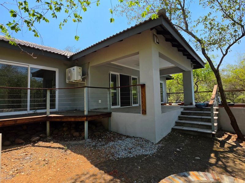 Rear view of the house featuring a covered patio, timber decking, and sliding glass doors leading into the living area.