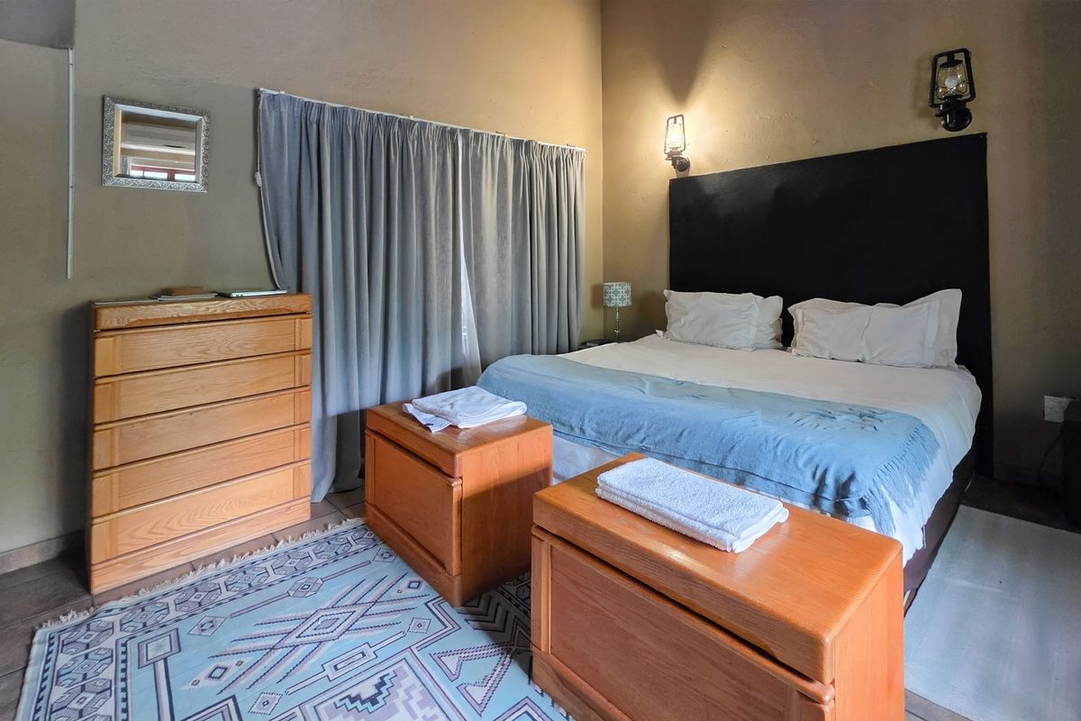 A cozy bedroom featuring neutral wall tones, built-in wall lighting, and window treatments, offering a comfortable and functional sleeping space.