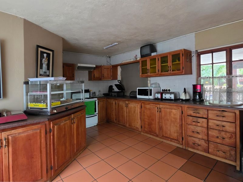 A dated kitchen featuring extensive wooden cabinetry, tiled flooring, and a built-in stove, offering significant potential for a modern renovation.